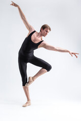 Obraz premium Ballet Dancer Man Posing in Dancing Stretching Pose With Hands Lifted While Standing in Ballance in Black Tights On White.
