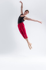 Naklejka premium Flying Ballet Dancer. Contemporary Art Ballet With Young Flexible Athletic Man Posing in Flying Dance Pose in Studio on White
