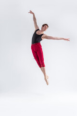 Naklejka premium Modern Ballet Dancer. Contemporary Art Ballet With Young Flexible Athletic Man Posing in Flying Dance Pose in Studio on White