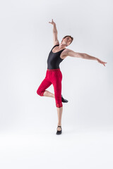 Fototapeta na wymiar Ballet Ideas. Contemporary Ballet of Flexible Athletic Man Posing in Red Tights in Dance Pose With Hands Lifted in Studio on White.