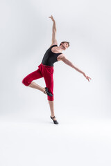 Ballet Ideas. Modern Ballet of Flexible Athletic Man Posing in Red Tights in Ballanced Dance Pose With Hands Lifted in Studio on White.