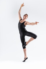Fototapeta na wymiar Sportive Caucasian Male Ballet Dancer Flexible Athletic Man Posing in Black Tights in Ballanced Dance Pose With Hands and Leg Lifted