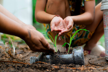 Little girl and mom grow plants in pots from recycled water bottles in the backyard. Recycle water bottle pot, gardening activities for children. Recycling of plastic waste - Powered by Adobe