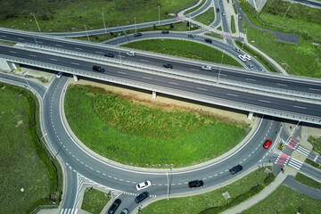 Aerial view of roundabout intersection with driving cars. Car traffic on highway with junction in...
