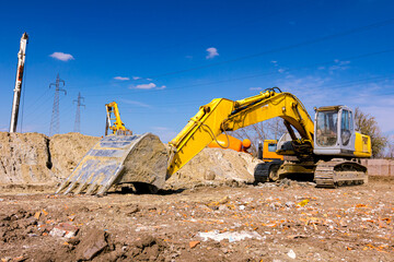 Obraz premium Low view on parked excavator, front bucket, undercarriage on building site