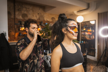 Fototapeta premium Preparations for the Halloween party, hairdresser finishing the hairstyle to the client in the beauty salon