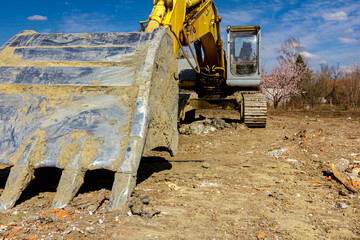 Low view on parked excavator, front bucket, undercarriage on building site
