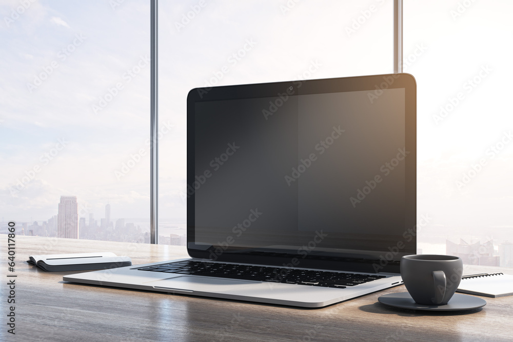 Poster Close up of laptop computer with empty mock up monitor, coffee cup and notepad placed on wooden desktop. Window with bright city view in the background. 3D Rendering.
