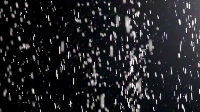 Raindrops fall diagonally changing direction. Rain pouring in different directions in black room on blurred background in slow motion