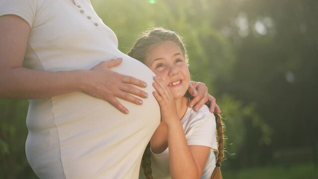 girl pregnant woman. daughter hugging her pregnant mother's belly. girl pregnant woman happy family kid dream concept. the girl loves her unborn brother, mother equally loves lifestyle two children