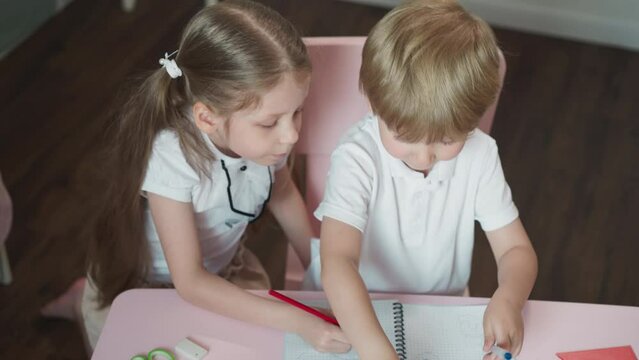 Caring sister draws picture for brother at desk at home