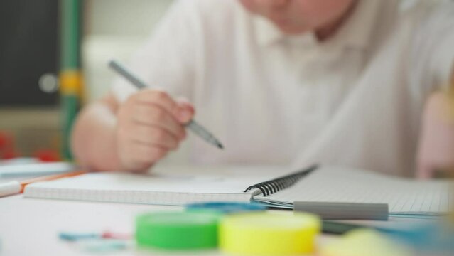 Toddler student draws with marker in exercise book at table