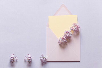 Happy birthday, mother's day, wedding composition. Blank greeting card, invitation and envelope mockup. Rectangular blank with delicate lilac flowers. Flat lay, top view. 