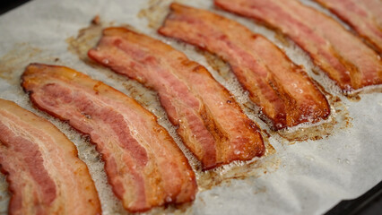Frying bacon slices in oven. Crispy pieces of fried delicious bacon. Traditional breakfast