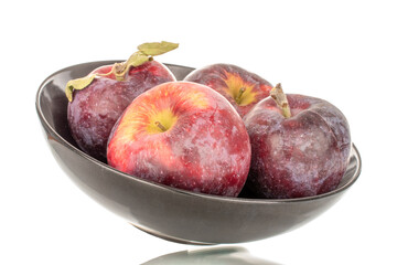 Several sweet organic red apples in a ceramic black plate, macro, isolated on white background.