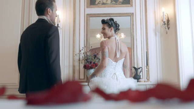 Slow motion shot of a groom kissing his wife on the shoulder in a private room