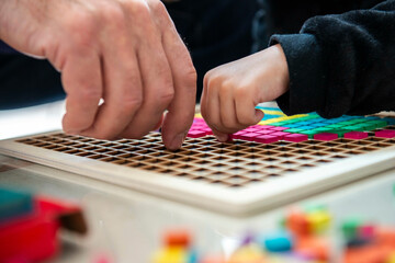 mains d'enfant et adulte sur un jeu de construction