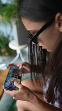 A pretty young woman engrossed in a video game on her mobile device.