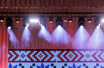An empty stage of the theater, lit by spotlights and smoke before the performance