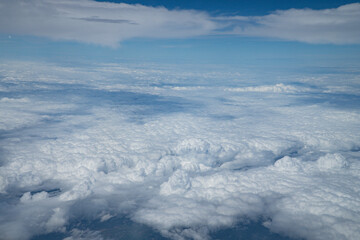 Beautiful cloudscape with blue sky. Wonderful panorama above white clouds as seen through window of an plane. Traveling by air concept