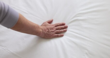 Man hand touches fabric of white mattress. Checking softness and choosing best type and quality