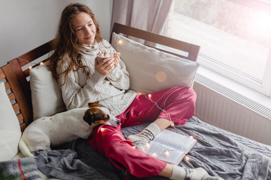 Young woman with dog drinking warm coffee at home