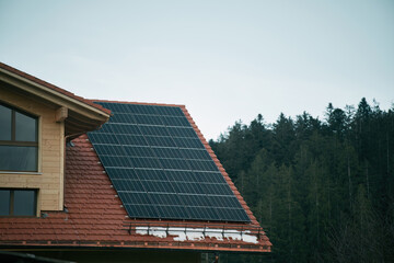 Fototapeta premium House with solar panels. Photovoltaic panels PV on the sky background. Blue solar panels. An alternative source of electricity.