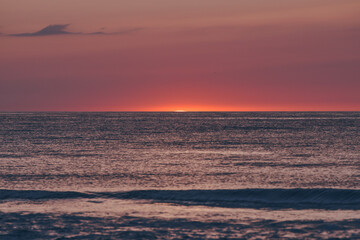 The glowing sun sinking on the horizon of the sea or ocean