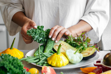 Woman's hands lay out fresh vegetables on a plate.