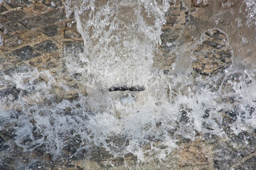Water jet in a fountain with water flowing out of the ground - Freshness concept