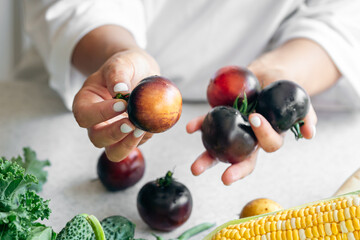 Black tomatoes in female hands close-up, cooking in the kitchen.