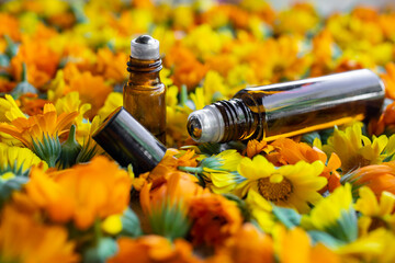 Roll on bottles with essential oil on marigold flowers bed, soft focus