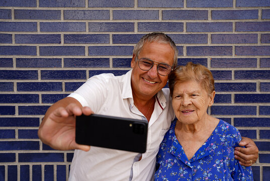 Smiling Older Mom And Her Son Taking A Selfie Together With A Mobile Phone. Video Call Family