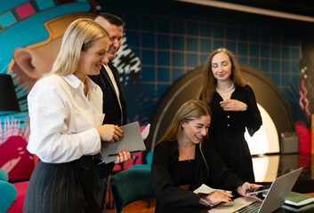 Team members gather to play new online boarding game. Involved team gather in coworking office zone...