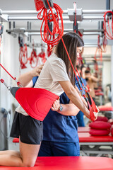 Rehabilitation specialist doing treatment on suspension straps to patient.