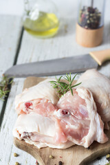 Fresh Chicken thigh meat on a cutting board with spices. On a wooden background.