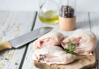 Fresh Chicken thigh meat on a cutting board with spices. On a wooden background.