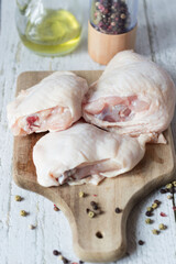 Fresh Chicken thigh meat on a cutting board with spices. On a wooden background.