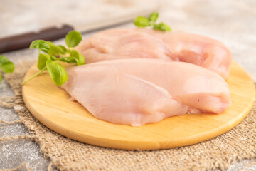 Raw chicken breast on brown concrete background. Side view, selective focus.
