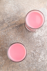 Sweet strawberry liqueur in glass on a gray concrete background. top view