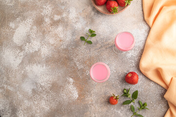 Sweet strawberry liqueur in glass on a gray concrete background. top view, copy space, flat lay.