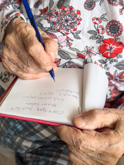 wrinkled hands of old woman writing shopping list in turkish