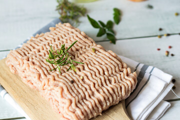 Raw ground turkey with rosemary and spices. Wooden on a white background.