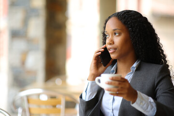 Black businesswoman talking on phone in a coffee shop