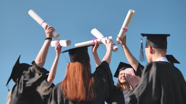College graduates join hands with their diplomas. The concept of friendship.