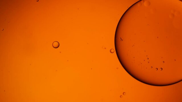 Gold artistic of oil drop floating on the water. Pastel color bubble for background. Orange background of oil drop.