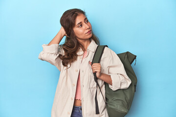 Young adventurer ready to explore with backpack touching back of head, thinking and making a choice.