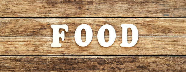 The word Food written on wood letters on wooden background, top view.