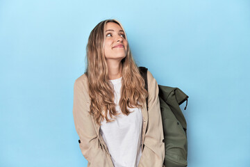 Blonde traveler with a travel backpack dreaming of achieving goals and purposes