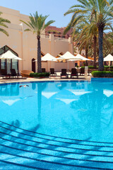 Swimming pool with clear water surrounded by palm trees in one of the best resorts